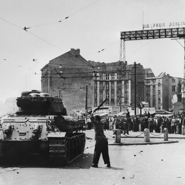 Schwarz-Weiß-Foto. Der Mann in einer Demonstration schägt mit einem Stock auf einer Panzer.  