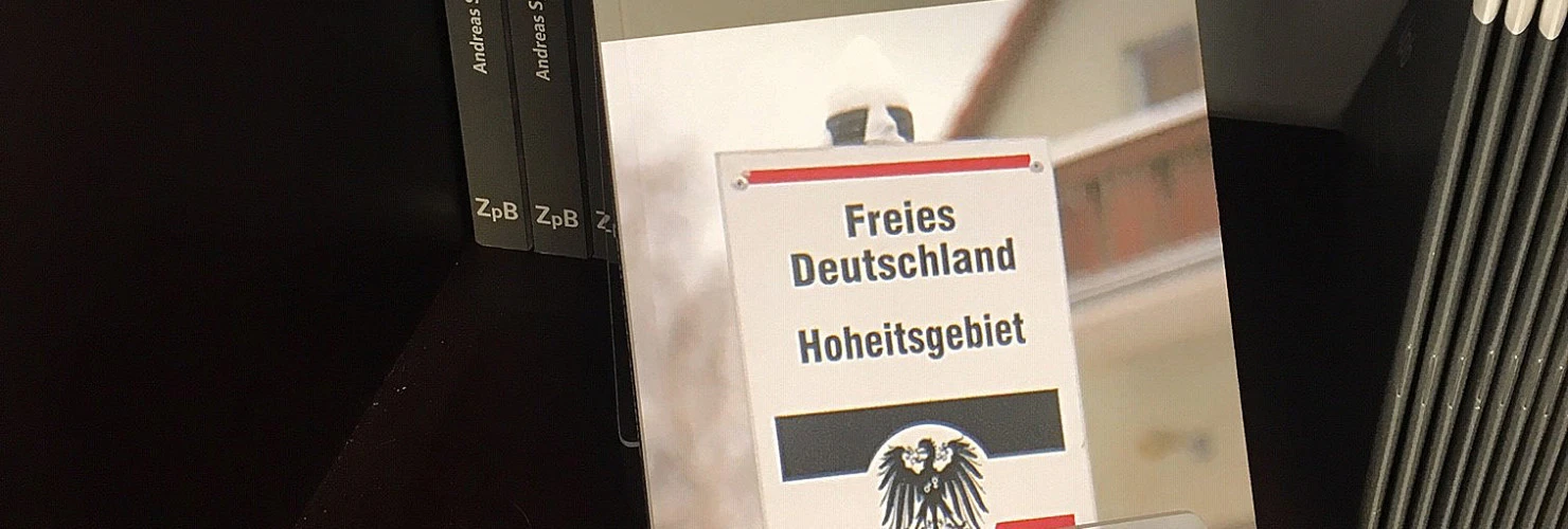 Ein Bild des Buches: "Reichsbürger"-Die unterschätzte Gefahr von Andreas Speit, mit dem Hintergrund der Bücher.  