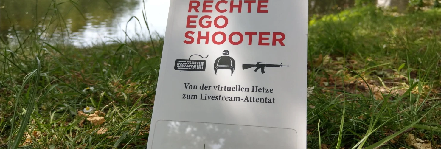 Ein Bild des Buches: "Rechte Egoshooter"- Von der virtuellen Hetze zum Livestream-Attentat, von Andreas Speit und Jean-Philipp Baeck, mit dem Hintergrund des Sees.  