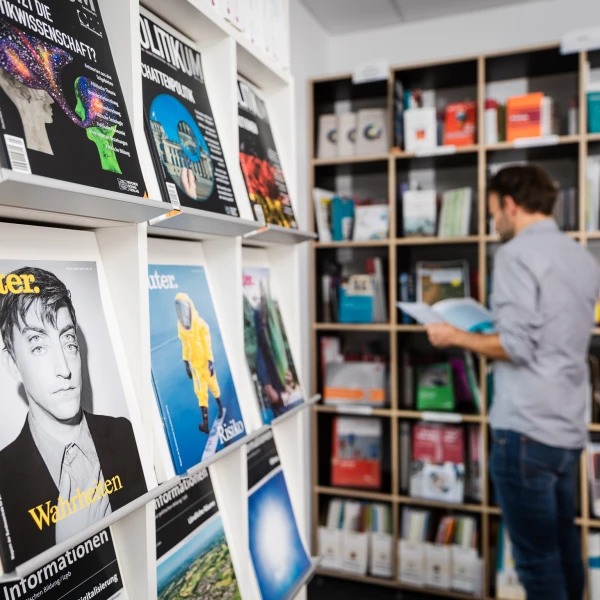 Ein Mann steht vor einem Bücherregal und liest ein Buch.  