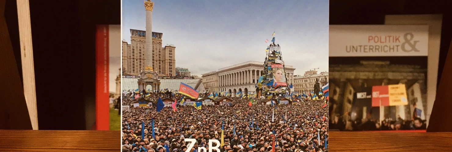 Das Buchcover von "Kleine Geschichte der Ukraine" mit einem Foto einer Demonstration von Tausenden von Menschen, die auf dem Hauptplatz von Kiew, dem "Maidan", stehen und verschiedene Fahnen schwenken.   