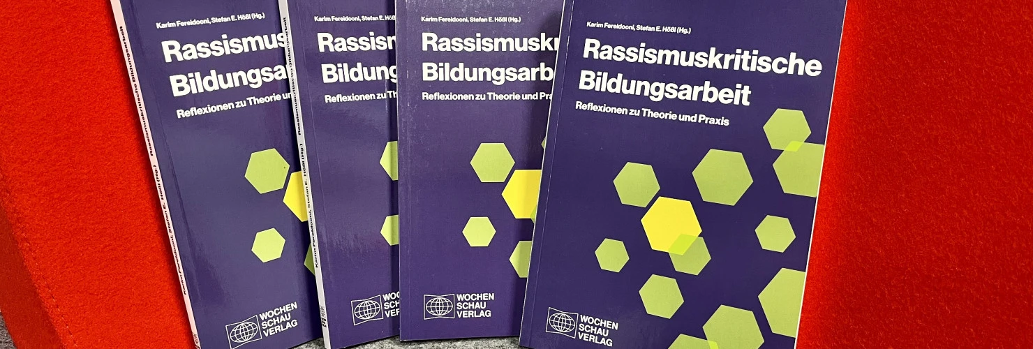 Die Buchcover von "Rassismuskritische Bildungsarbeit. Überlegungen zu Theorie und Praxis". Der Umschlag ist violett, der Titel weiß und zur Illustration sind grüne Fünfecke eingearbeitet.  