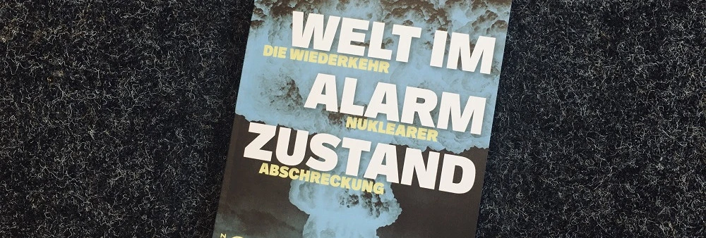 Ein Bild des Buchcovers: " Welt im Alarmzustand. Die Wiederkehr nuklearer Abschreckung" mit dem Foto einer Atombombenexplosion. Der Titel auf dem Buch ist weiß und gelb geschrieben.  