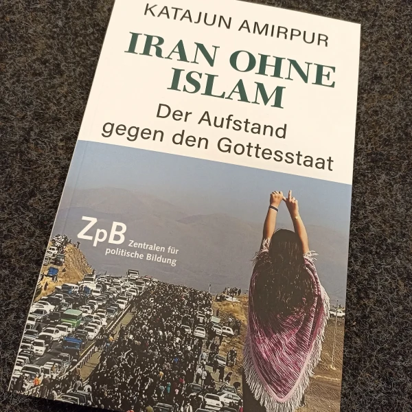 Das Buchcover "Iran ohne Islam. der Aufstand gegen den Gottesstaat" von Katajan Amirpur zeigt eine Frau, die ihre Hände hebt und erhöht vor einer Masse aus Menschen steht.  